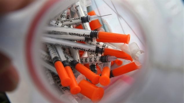Not a pretty picture, the dregs of heroin. We see a container filled with hypodermic needles. They have orange tops and silver bodies. Very, very scary.