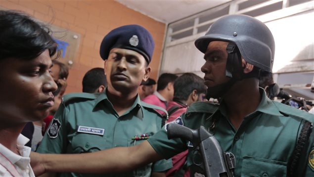 Des policiers de Dhaka, au Bangladesh, tentent de contrôler les curieux près de l’immeuble où on a retrouvé le corps des deux hommes assassinés.