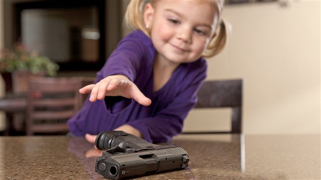 Une petite fille tente de prendre un pistolet Une petite fille tente de prendre un pistolet