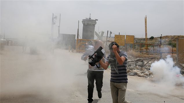صحافيّون فلسطينيّون يهربون بعد أن أطلقت القوّات الاسرائيليّة قنابل مسيلة للدموع خلال مظاهرة دعم للصحافيّين الفلسطينيّين في اليوم العالمي لحريّة الصحافة
