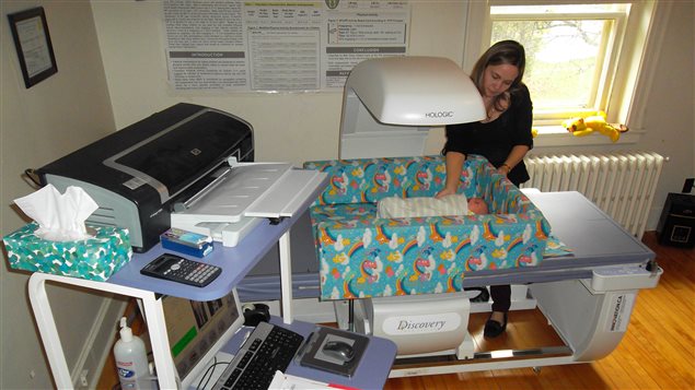 Research nurse Catherine Vanstone setting up the equipment to measure an infant; the machine is a densitometer used to measure quality of infant growth including muscle, fat and bone across infancy and into the toddler years. This is the same equipment that is used in adults for measuring bone health.