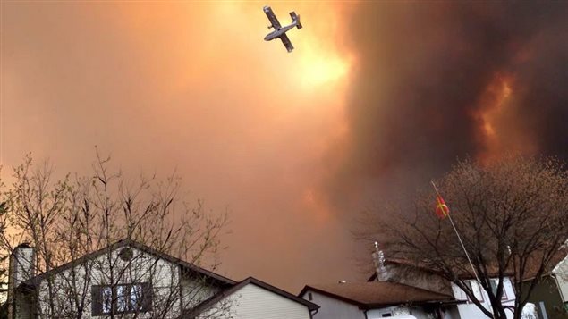 Un avion survole un quartier en feu de Fort McMurray.