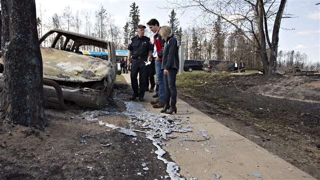  Fort McMurray Fire Chief Darby Allen, left to right, Prime Minister Justin Trudeau and Alberta Premier Rachel Notley look over a burnt out car during a visit to Fort McMurray, Alta., on Friday, May 13, 2016. 