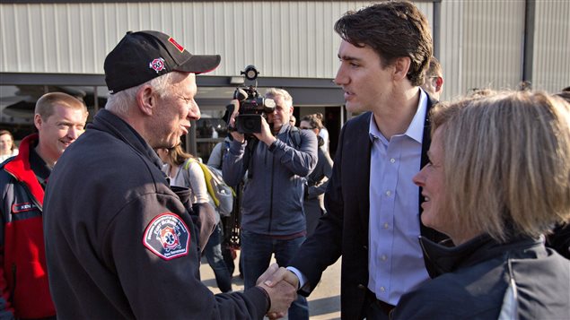  Prime Minister Justin Trudeau shakes hands with Fort McMurray fire chief Darby Allen as Alberta Premier Rachel Notley (right) looks on in Edmonton, Friday, May 13, 2016