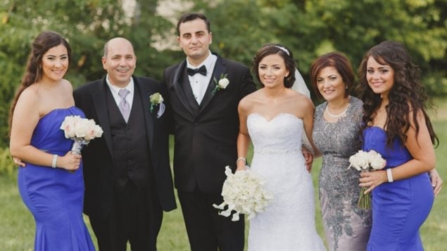 Medhat Tanious, second from left, at the wedding of his oldest daughter Marina in 2015.  It's one of those line photos one gets at a wedding. The family is extremely handsome and lovely and smiling broadly. Mr. Tanious, the father of the bride, is balding with grey hair. He is heavy-set and wears a a dark suit and vest as he hugs the bridegroom to his left. Marina, the bride, wears white and holds her corsage in her right hand. Her mother to her left wears a classy grey long dress. Marina's sisters stand at each end of the line wearing purple-blue dresses. 