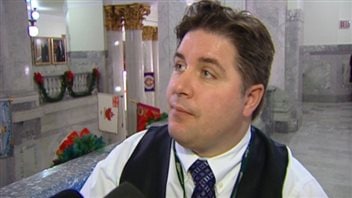 Some veterans wonder if Minister of Veterans Affairs Kent Hehr can speed things up when it comes for finding jobs in the public service. We see Mr. Hehr looking up to his right. He has relatively long, slightly styled brown hair. He wears a dark blue vest, white dress shirt and blue, patterned tie. He has gentle eyes and a kind face.