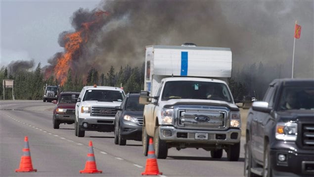  Evacuees drive past a fireball as a wildfire rips through the forest beside Highway 63, some 16 kilometres south of Fort McMurray, Alta. on Saturday, May 7, 2016.