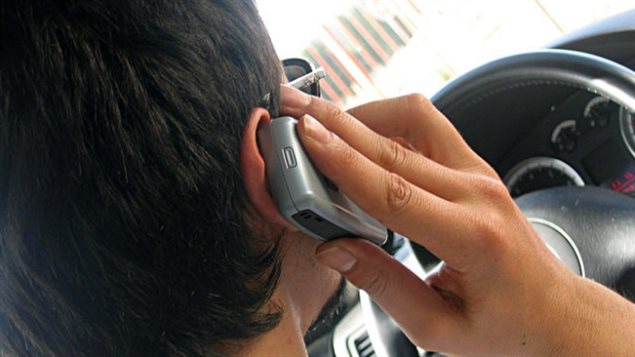 سائق يستخدم الهاتف الخليوي أثناء قيادة سيّارته
