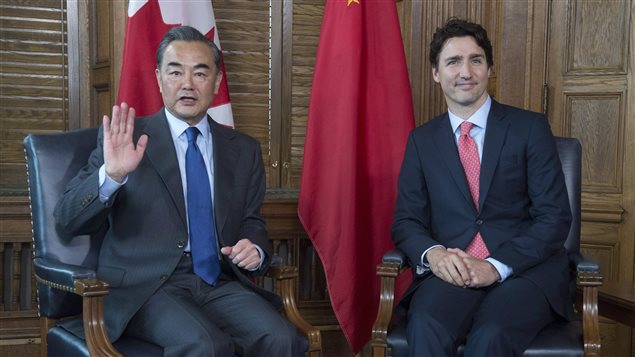 Prime Minister Justin Trudeau, right, meets with Chinese Foreign Minister Wang Yi on Parliament Hill in Ottawa on Wednesday--before Wang's verbal fireworks. Both men are seated and dressed in classy, dark suits with the flags of both nations behind them. Wang is waving with his right hand. His mouth is slightly agape. Trudeau's lips show are slightly pursed and grim.