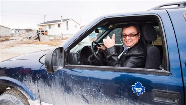 eet with Prime Minister Justin Trudeau in Ottawa on June 13. We see a man wearing a black leather jacket in the driver's seat of blue pickup truck giving up a thumbs up sign through the open window. He wears dark-rimmed tinted glasses and is smiling. On thAttawapiskat Chief Bruce Shisheesh (above) will me side of the truck sits the blue and white logo of the Toronto Maple Leafs.