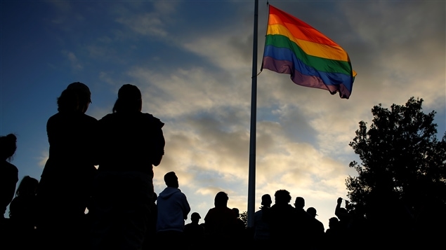 Réunis devant un drapeau arc-en-ciel à la mémoire des victimes de la fusillade d’Orlando, en Floride