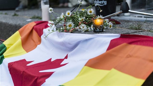 Mourners created a Canadian flag with rainbow borders to place with candles at the Toronto vigil.