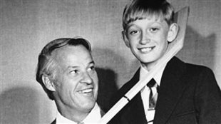 Gordie Howe and Wayne Gretzky in 1972. Gretzky patterned his public persona on lessons he learned from Howe. We see a somewhat buck-toothed, mob-topped, blond Gretzky smiling at the camera as Howe who is sitting to Gretzky's right, playing wraps the blade of a hockey stick under Gretzky's chin. Gretzky was 
