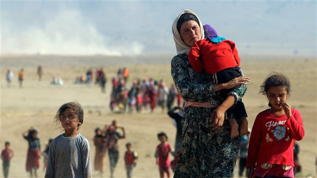  Displaced people from the minority Yazidi sect, fleeing violence from forces loyal to the Islamic State in Sinjar town, walk towards the Syrian border on the outskirts of Sinjar mountain near the Syrian border town of Elierbeh of Al-Hasakah Governorate in this August 11, 2014.