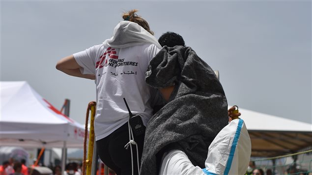 عضوة في منظمة أطباء بلا حدود تساعد مهاجرا بالنزول من قارب أنقذه في المتوسط الشهر الماضي 
