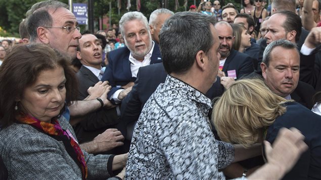 Le premier ministre Couillard est forcé de quitter la rue Sainte-Catherine où un individu l'a agressé. Le premier ministre Couillard est forcé de quitter la rue Sainte-Catherine où un individu l'a agressé.