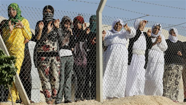 Yazidi refugee women stand behind fences as they wait for the arrival of United Nations High Commissioner for Refugees Special Envoy Angelina Jolie at a Syrian and Iraqi refugee camp in the southern Turkish town of Midyat in Mardin province, Turkey, June 20, 2015. 