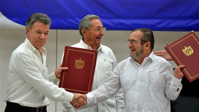 El presidente colombiano, Juan Manuel Santos, y el jefe de las FARC Rodrigo Londoño se dan la mano junto al líder cubano Raúl Castro.