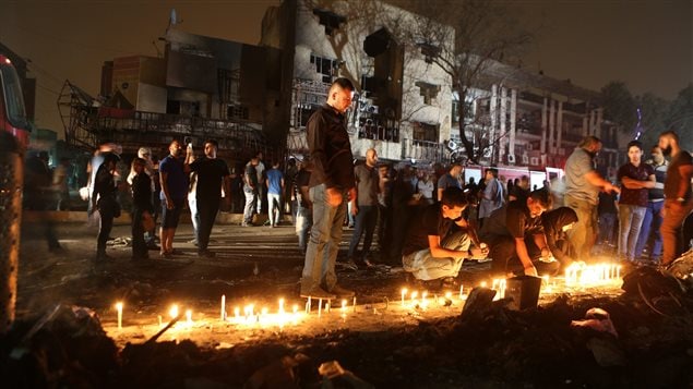  People light candles at the scene of a massive car bomb attack in Karada, a busy shopping district where people were shopping for the upcoming Eid al-Fitr holiday, in the center of Baghdad, Iraq, Sunday, July 3, 2016. 