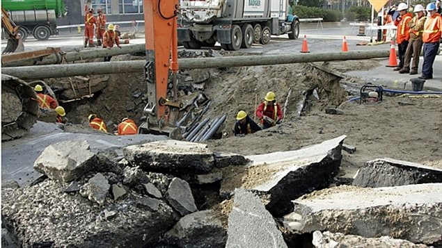 Crews from London Hydro clear debris from a giant sinkhole that opened when a water main broke early in the morning in the middle of a downtown intersection in London, Ont., on Oct. 31, 2007. The street collapse led to traffic backups and a power outage, closing much of the downtown area for the day