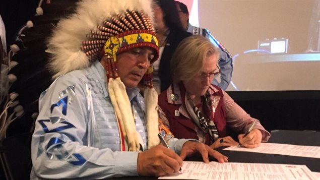 El jefe indígena Perry Bellegarde y la ministra canadiense de Asuntos Indígenas, Carolyn Bennett, firman un memorando de entendimiento para crear una nueva relación fiscal.