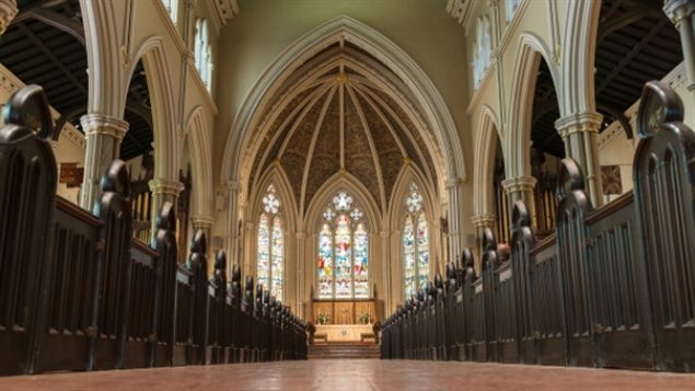 The Anglican Church of Canada will allow same-sex marriages, reversing a decision made Monday night after a voting error was discovered. We see a low angle shot from the back of the church looking up along the main aisle toward the altar, which sits amid huge stained-glass windows. The predominant architecture is high, rounded arches.