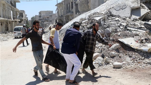 رجال ينقلون جثة شخص قرب مبنى مدمَّر عقب غارة جوية أمس على حي الحلوانية في حلب الواقع تحت سيطرة القوات المعارضة للرئيس بشار الأسد. 