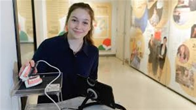 Emma Mogus, We see a lovely young woman with  long brown hair and a gorgeous smile sitting next to a table on which sits her creation, the  TiC, or Tongue-Interface-Communication, which will make it possible for many disabled people to have greater access to the Internet.