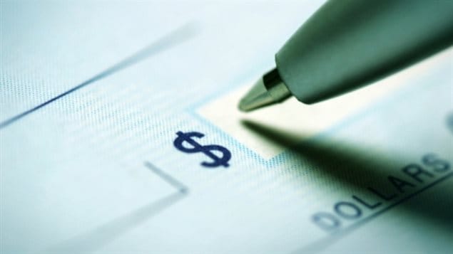 The federal government rolled out its new automated pay system, Phoenix, last winter. The result: thousands of Public Service Alliance of Canada members have written letters of complaint about not getting their proper compensation. We see the tip of a ballpoint pen filling in a blank check next to a dollar sign.
