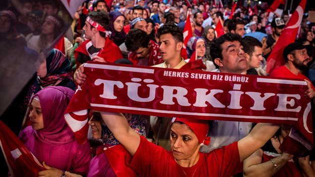 Une femme tient une bannière sur laquelle on peut lire : Turquie