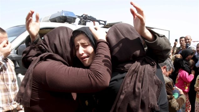 Members of the minority Yazidi community have been trying to flee ISIS since the militant group overran their villages in northwestern Iraq in 2014. We see a woman in tears in the centre of the photo. She is being comforted and hugged by two other women. All are dressed in black.