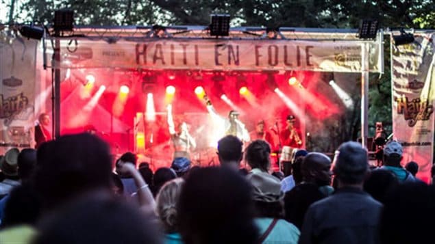 Canada's Haitian community is set to begin a week-long celebration of their culture. We see a bandstand bathed in red and the audience in front of it. A large banner over the stage says, 'Haiti en folie.'