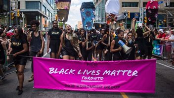 Black Lives Matter Toronto, which was invited by Pride Toronto to help lead this year's parade, brought the procession to a standstill until a list of demands were met. The Vancouver chapter has backed off a threatened protest in Vancouver on Sunday but says it won't participate either. We see a group of young (mostly black) young (in their twenties) men and women dressed in black marching behind a pink banner with the words 