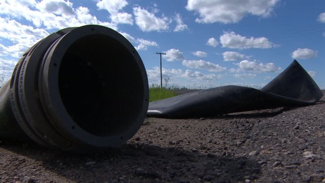 The city of Prince Albert is rolling out a 30-kilometre waterline connecting its water treatment plant to the South Saskatchewan River following last Thursday's Husky Energy oil spill. We see a giant, dark tube sitting on the brown dirt below deep blue skies on the prairie landscape.
