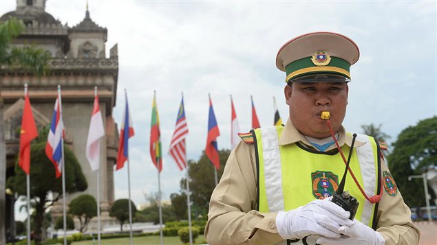 A traffic policeman directs trafic next to the victory tower Patuxay in the Laos capital of Vientiane on July 23, 2016, as the country hosts the 49th annual ministerial meeting of the South East Asian Nations (ASEAN).