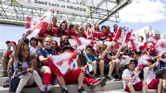  Members of Canada’s Women’s Rugby Sevens Olympic team pose for a photo opportunity with flag waving school children before an announcement by Canadian Olympic Committee (COC) and Rugby Canada in Toronto on Tuesday, July 26, 2016. 