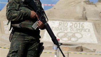 A Brazilian Armed Forces soldier patrols on Copacabana beach in Rio. Security will be super tight at the Games. We see a soldier from the neck down dressed in battle dress. He holds a rifle pointed downwards toward the right of the photo.