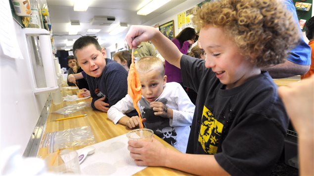  Audubon Elementary School fourth-graders Sam Tucker, 9, front left, and Gavin Crabtree, 9, center, watch as ten-year-old Terry Geary pulls a handful of *gluep* out of a plastic cup inside the Kentucky Department of Agriculture’s Mobile Science Activity Center (MSAC) outside the Worthington Road school in Owensbro, Ky., on Thursday, Nov. 29, 2012. 