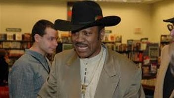 Make a high enough bid and you get win a jock strap once worn by Joe Frazier (above). We see Joe in a tan sports coat and wearing a black cowboy hat.