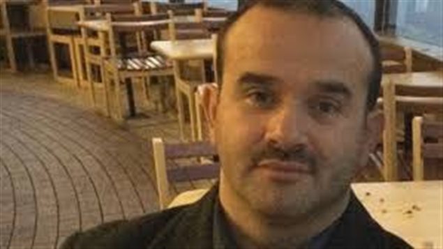 Davud Hanci is one of two dual Canadian-Turkish citizens currently being held in Turkey in the wake of the July 15 failed coup. So far, Canadian diplomats have been rebuffed in attempts to meet with them. We see a man from the shoulders up. His dark hair is beginning to recede. He has dark eyes wears a thin moustache.