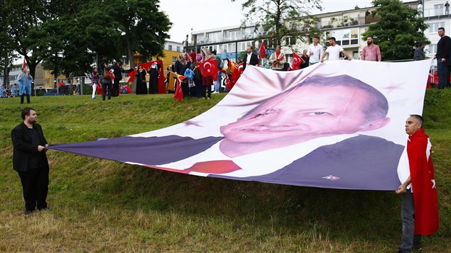 مناصرون للرئيس التركي رجب طيب أردوغان يرفعون صورة ضخمة له خلال تجمع لمؤيديه في أوساط الجالية التركية في مدينة كولونيا الألمانية في 31 تموز (يوليو) الفائت