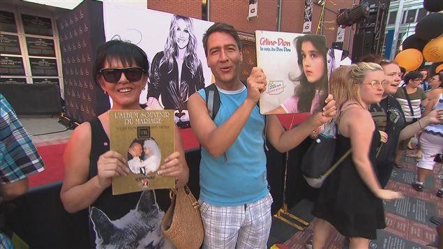 Des fans de Céline Dion se tiennent sur le tapis rouge et montrent des pochettes d’album de la chanteuse avant son spectacle au Centre Bell de Montréal, le 31 juillet 2016.