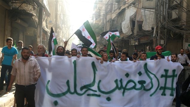 متظاهرون في حلب يحملون علم الجيش السوري الحرّ ويرفعون لافتة كُتب عليها: الغضب لحلب