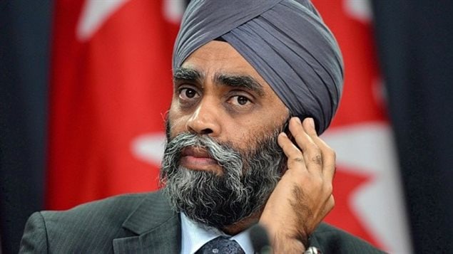 Defence Minister Harjit Sajjan is leading fact-finding trip to five African countries to study the possibility of sending peacekeepers to the continent. His delegation includes former UN commissioner for human rights Louise Arbour and retired general Romeo Dallaire, who commanded a peacekeeping mission during the Rwanda genocide in 1994. We see a dark-skinned man full face. He wears a dark-blue turban, has dark, gentle eyes, bushy eye brows and a beard and moustache that is full and more grey than dark. He has his left hand up to his ear.