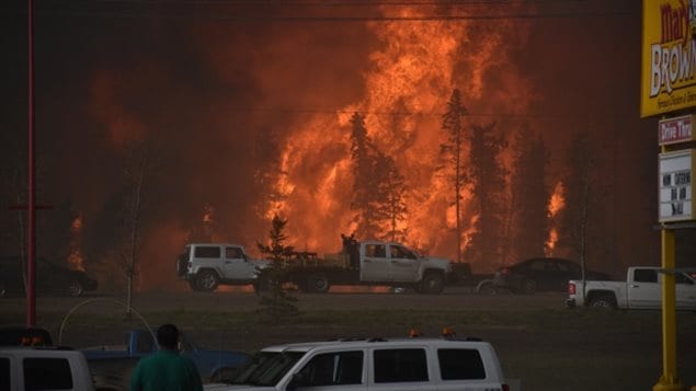 Almost a quarter of those forced to flee through flames from Fort McMurray on May 3 (above) are now seeking help for the trauma that the exodus brought forth. We see a fierce picture of a giant ball of flames rising high in the air as trucks and cars pass in front trying to get out of town.