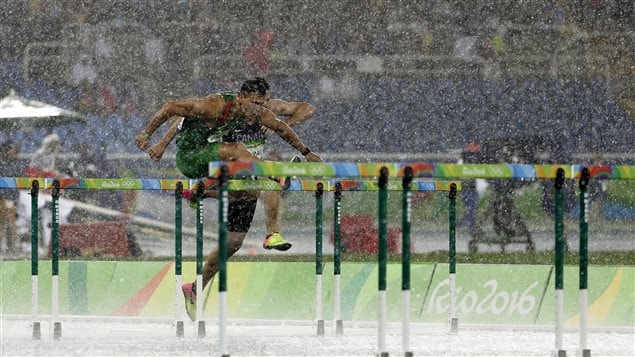 Hungary’s Balazs Baji, left, and Canada’s Johnathan Cabral ran in pouring rain in the men’s 110-metre hurdles heat.