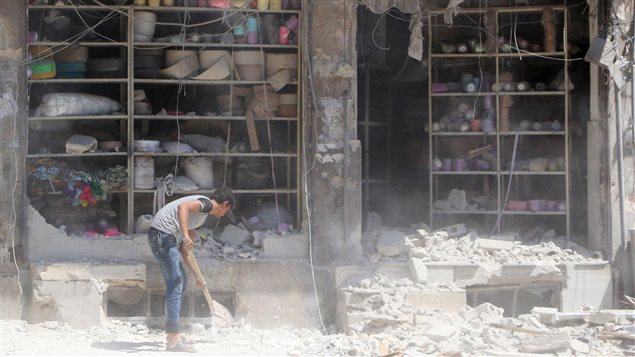رفع الركام من أمام متجر دمّره القصف في حلب