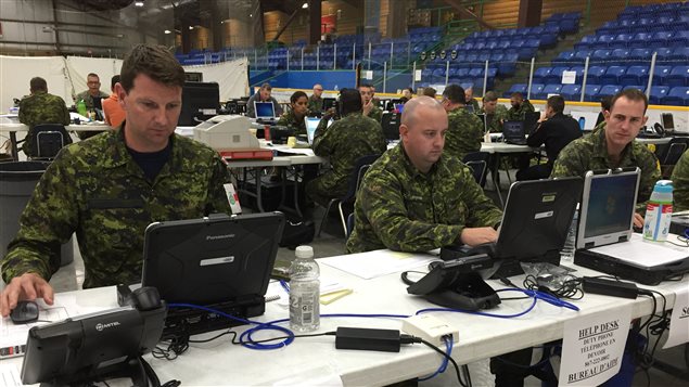 des militaires assis à leur poste de travail dans un aréna