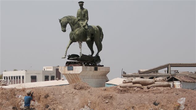 Un rebelde kurdo dispara contra una estatua del hermano del presidente sirio, Bachar Al Assad.