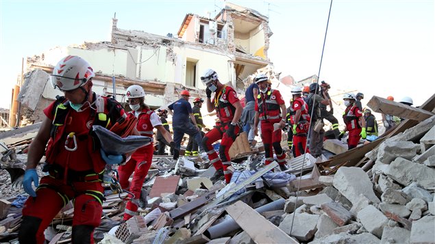 Des secouristes marchent à travers les décombres à Amatrice, au centre de l’Italie. 
